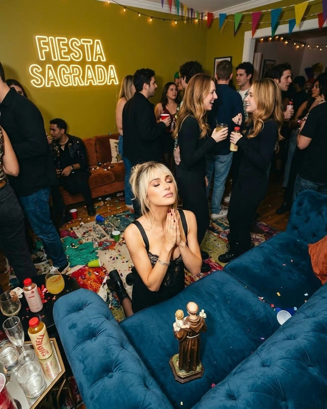 Una invitada de rodillas en un sofá azul, celebrando con un trofeo en una fiesta de Miércoles de Solteros